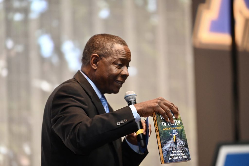 MTSU President Sidney A. McPhee holds the 2022 Summer Reading Program book, "Walking to Listen: 4,000 Miles Across America, One Story at a Time," that new MTSU students will be required to read before the start of classes in August. He shared this during the president's Celebration of Scholars Monday, Feb. 21, in the Student Union Ballroom. About 100 high school seniors, who have been offered major scholarships to attend MTSU, attended the event. (MTSU photo by James Cessna)
