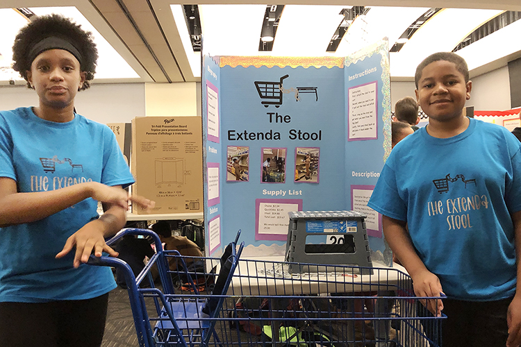 Makiya Lankford, left, and Richard Finley, both fifth graders at East Side Elementary School in Shelbyville, Tenn., pose in their customized T-shirts with “The Extenda Stool,” their invention to help shoppers more safely reach grocery items, in Middle Tennessee State University's Student Union Ballroom Thursday, Feb. 17, at the 29th annual Invention Convention. The pair were among 700-plus fourth-, fifth- and sixth-grade students from 36 schools across the Midstate who showcased their inventions to make life easier, their newly invented games and their entrepreneurship plans for their projects. (MTSU photo by Gina E. Fann)
