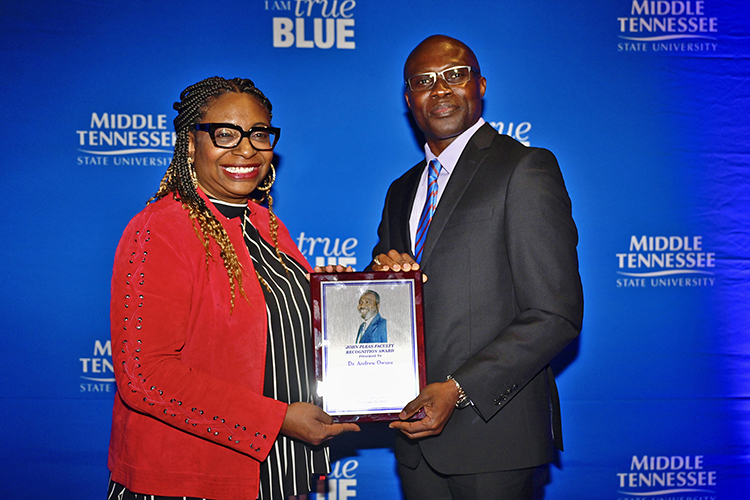 Dr. Andrew Owusu, right, professor of health and human performance at MTSU, receives the 2022 John Pleas Faculty Award from Dr. Jennifer Woodard, assistant dean of the College of Media and Entertainment and 2021 Pleas Award recipient, at a Feb. 23 ceremony in James Union Building. (MTSU photo by Cat Curtis Murphy)