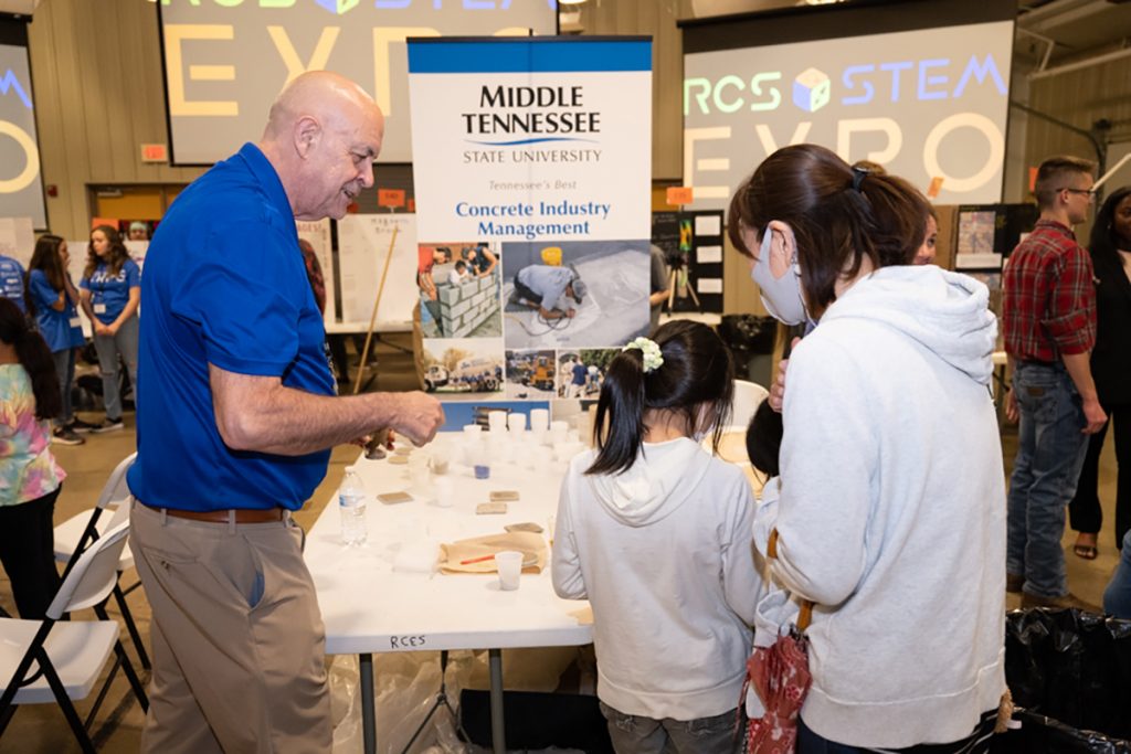 MTSU School of Concrete and Construction Management Director Kelly Strong, left, shows participants at the Rutherford County Schools' STEM Expo how to make concrete coasters. MTSU's College of Basic and Applied Sciences sponsored a $1,000 scholarship and brought other swag to the fourth annual event. (MTSU photo by James Cessna)