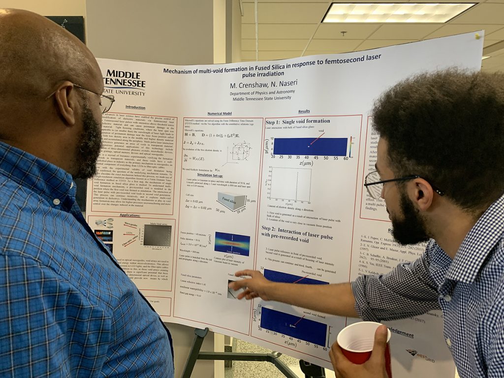 MTSU Physics and Astronomy professor Daniel Erenso, left, listens as physics major Miles Crenshaw explains his research March 17 during the first physics poster exhibit in Wiser-Patten Science Hall. The poster research range included quantum materials, nanomaterials, semiconductors, physics, biophysics, optics, high-energy physics and astrophysics. (MTSU photo by Randy Weiler)