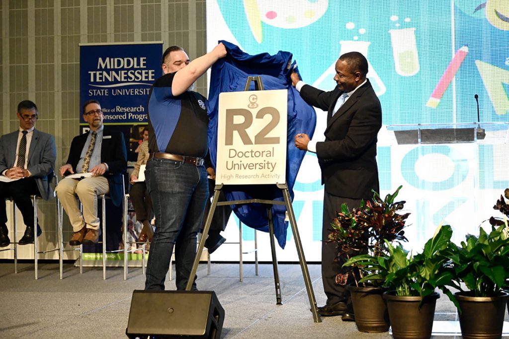 Middle Tennessee State University President Sidney A. McPhee, right, and David Butler, left, vice provost for research and College of Graduate Studies dean, unveil the replica of a future plaque commemorating the university’s historic elevation to R2 “High Research Activity” Carnegie classification status on March 25, 2022, at the ballroom of the Student Union Building on campus. (MTSU photo by J. Intintoli)