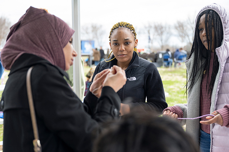 Salwi Alrubaye, left, a volunteer at the Festival of Veils, demonstrates stringing prayer beads for Lauren and Paige Surles. The festival was held March 19 on the Student Union Commons. (MTSU photo by Cat Curtis Murphy)