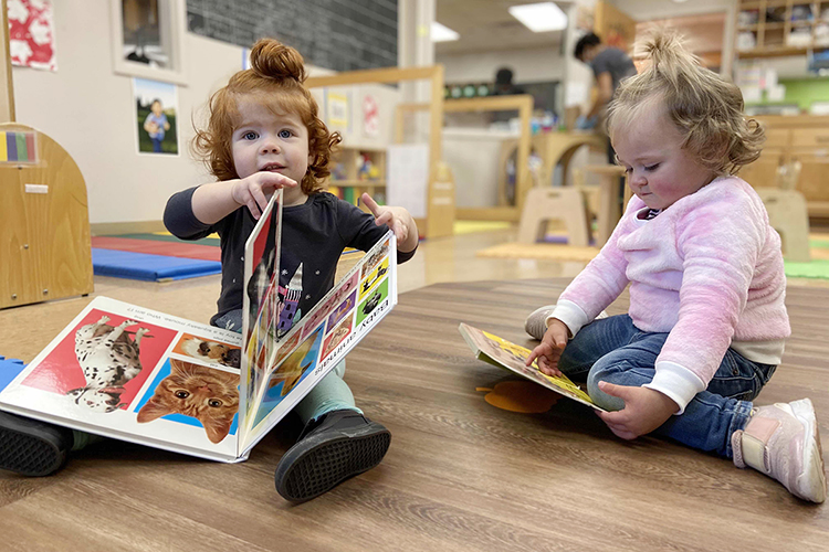 Two of the little learners at MTSU's Ann Campbell Early Learning Center, wearing matching topknot ponytails, take a reading break in a center classroom in this file photo. The nonprofit, inclusive preschool, an arm of MTSU’s College of Education, is welcoming supporters of all ages to its 15th annual "Saddle Up" fundraiser on Saturday, April 30. For more information, visit https://www.mtsu.edu/acelearningcenter/saddleup.php. (Photo courtesy of the Ann Campbell Early Learning Center at MTSU)