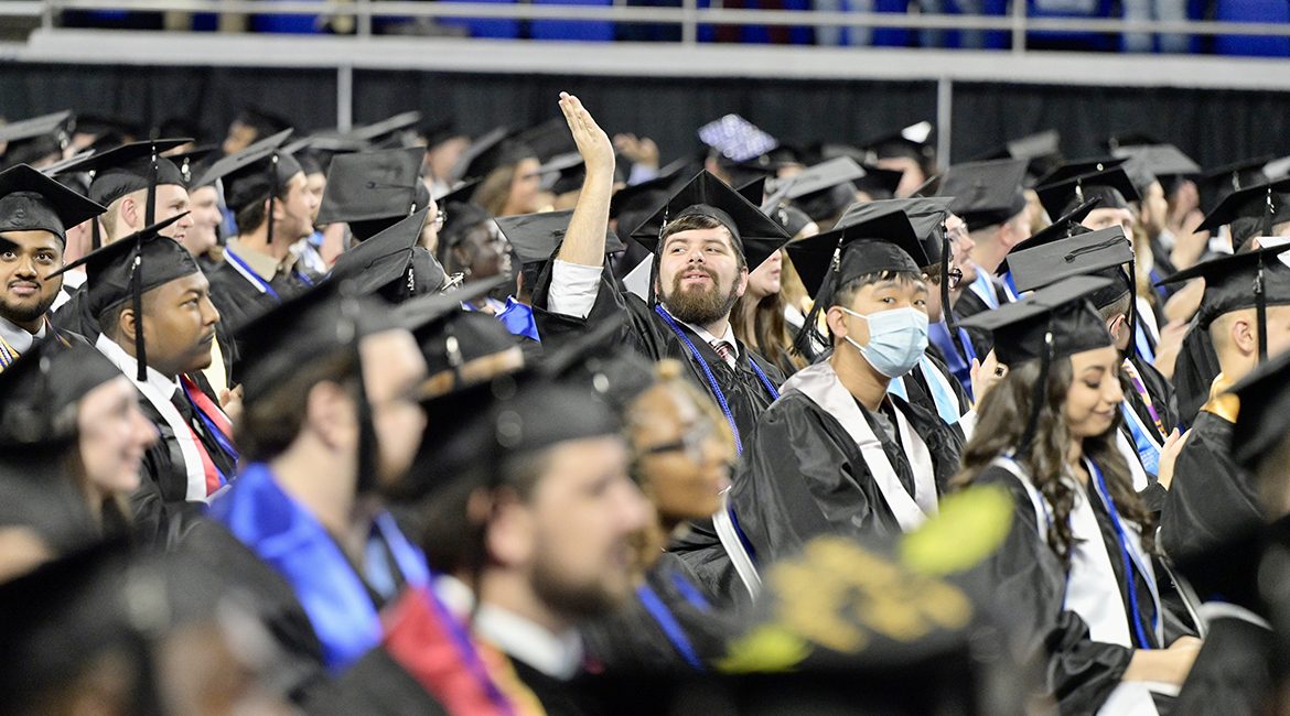 A graduating MTSU student, surrounded by his classmates, acknowledges a supporter in the audience in Hale Arena inside Murphy Center during fall 2021 commencement ceremonies last December. The university will award degrees to more than 2,475 members of the first Class of 2022 on Saturday, May 7, during three ceremonies at its spring 2022 commencement event inside Murphy Center. (MTSU file photo by Andy Heidt)