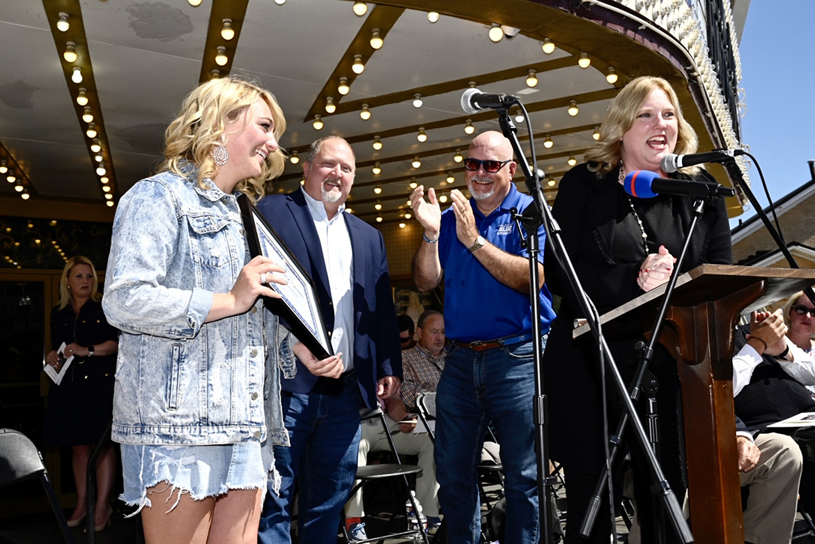 MTSU College of Media and Entertainment Dean Beverly Keel, right, presents alumna and ‘American Idol’ finalist Hunter ‘HunterGirl’ Wolkonowski, far left, with an honorary professorship Tuesday, May 17, during a celebration of her successes outside the Oldham Theatre located on the public square of her hometown of Winchester, Tenn. Assisting with the presentation is MTSU associate professor of songwriting Odie Blackmon, second from left, and Andrew Oppmann, vice president for marketing and communications. (MTSU photo by J. Intintoli)
