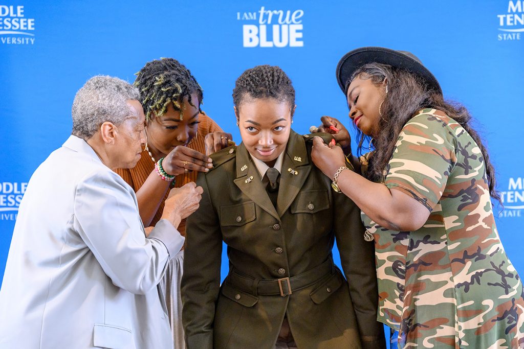 Newly commissioned U.S. Army 2nd Lt. Charity Savage, center, of Memphis, Tenn., bends slightly, allowing grandmother Mary Savage, left, best friend Ariel Smith and mother Tammy Savage to pin on the bars to her uniform Friday, May 6, during the MTSU Blue Raider Battalion spring commissioning ceremony in the Tom H. Jackson Building’s Cantrell Hall. Charity Savage, who will graduate Saturday, May 7, will be receiving her Master of Science in Professional Science in biotechnology. (MTSU photo by J. Intintoli)