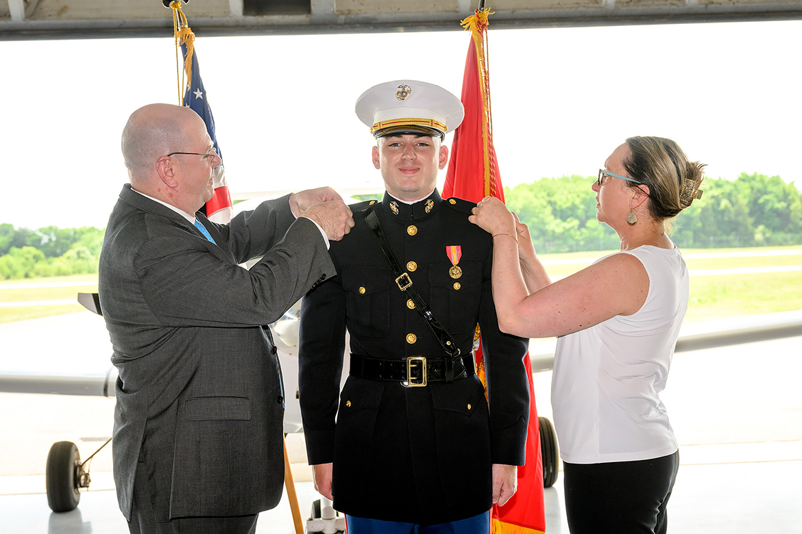 Retired U.S. Marine Lt. Col. John Wehner, left, and former U.S. Navy Nurse Corps member Suzanne Wehner pin gold bars onto their son Isaac Wehner’s uniform May 20 in the Donald McDonald Hangar at MTSU’s Flight Operations Center at Murfreesboro Airport. The commissioning ceremony commemorated Isaac Wehner becoming a second lieutenant in the Marine Corps. He is the sixth in his family to become a Marine. (MTSU photo by J. Intintoli)