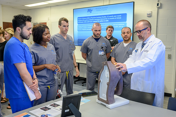 Travis Layne, Middle Tennessee State University director of didactic education, far right, demonstrates a technique on a medical mannequin to students during the grand opening event for the university’s new Physician Assistant Studies graduate program at the Cason Kennedy Nursing Building on campus on May 13, 2022. (MTSU photo by J Intintoli)