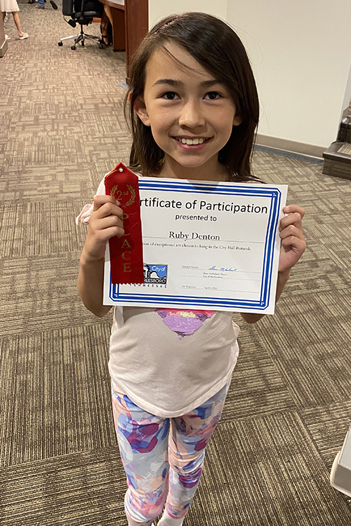 Erma Siegel Elementary fourth grader Ruby Denton holds the second place ribbon and certificate she received for her artwork entered in the 2021-22 Murfreesboro Student Art Show. (Photo courtesy of Ed Denton)
