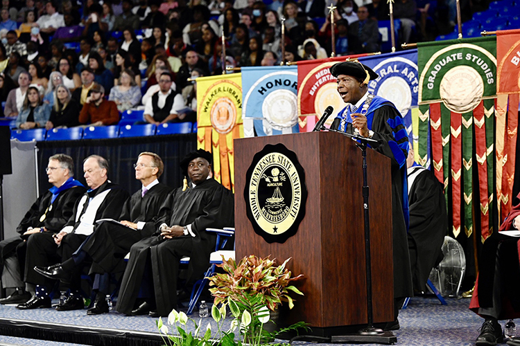 Middle Tennessee State University President Sidney A. McPhee, standing, makes a point Saturday, May 7, during the university's spring 2022 morning commencement ceremony in Hale/Earle Arena inside Murphy Center. Listening are, seated from left, University Provost Mark Byrnes, MTSU Board of Trustees President Steve Smith, former Tennessee Gov. Bill Haslam and Prime Minister Philip Edward Davis of the Bahamas. Davis was the morning event's guest speaker, and he and Haslam also received honorary doctorates. MTSU awarded 2,474 degrees — 2,041 to undergraduates and 433 to graduate students — during its three-ceremony spring 2022 commencement event. (MTSU photo by J. Intintoli)