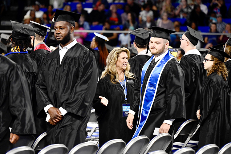 Yvonne Elliott, center, executive aide for the Center for Popular Music at Middle Tennessee State University, helps direct prospective graduates to their assigned seats in Hale/Earle Arena inside Murphy Center Saturday, May 7, in preparation for the university's spring 2022 morning commencement ceremony. MTSU awarded 2,474 degrees — 2,041 to undergraduates and 433 to graduate students — during its spring 2022 commencement event. (MTSU photo by J. Intintoli)