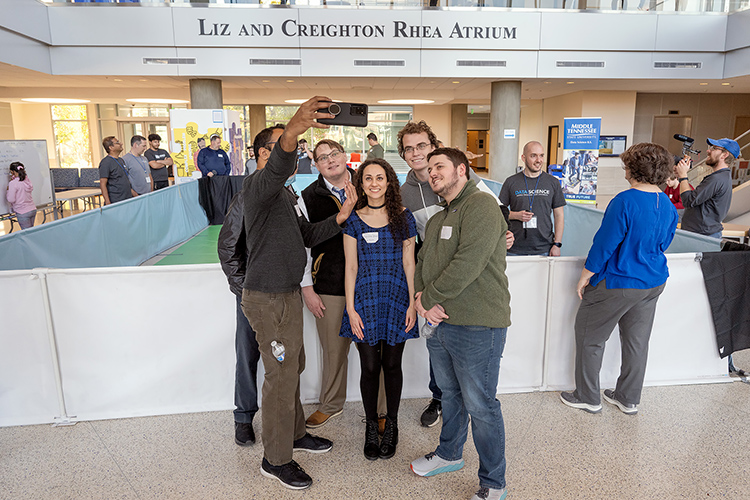 Spring 2022 data science program graduate David Jean, third from left in tie, poses for a group photo in the Science Building atrium with members of MTSU's Data Science Club who participated in the November 2021 Deep Racer event, a partnership between the MTSU Data Science Institute and Amazon Web Services in which MTSU students and area high school students programmed and raced autonomous vehicles. (MTSU file photo by Cat Curtis Murphy)