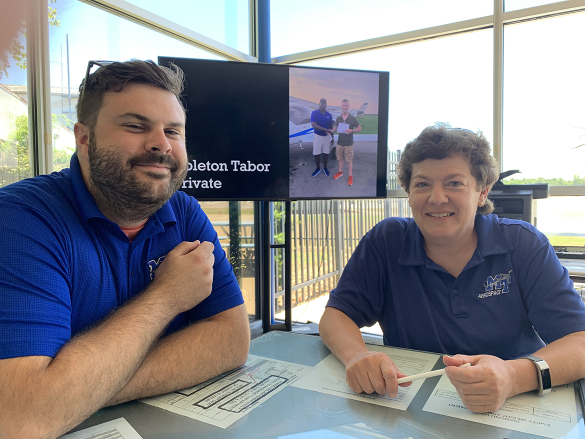 Michael Gref, left, chief flight instructor at the MTSU Flight Operations Center at Murfreesboro Airport, and professor Wendy Beckman discuss the study the Aerospace Department performed earlier this year. The investigation involved the pilot examiner shortage. (MTSU photo by Randy Weiler)