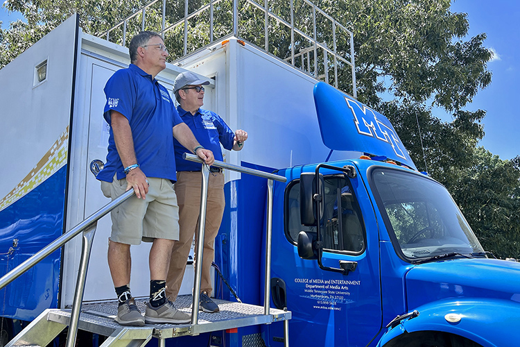 MTSU Provost Mark Byrnes, left, and Greg Pitts, journalism and strategic media school director, stand at the entrance of the university’s $1.4 million Mobile Production Lab during their visit Friday, June 17, to the 2022 Bonnaroo Music and Arts Festival in Manchester, Tenn. The lab, fondly known as “The Truck,” serves as the home base for the team of MTSU students, faculty and staff providing audiovisual and streaming support of performances as well producing original content at the festival being held Thursday-Sunday, June 16-19. (MTSU photo by Andrew Oppmann)