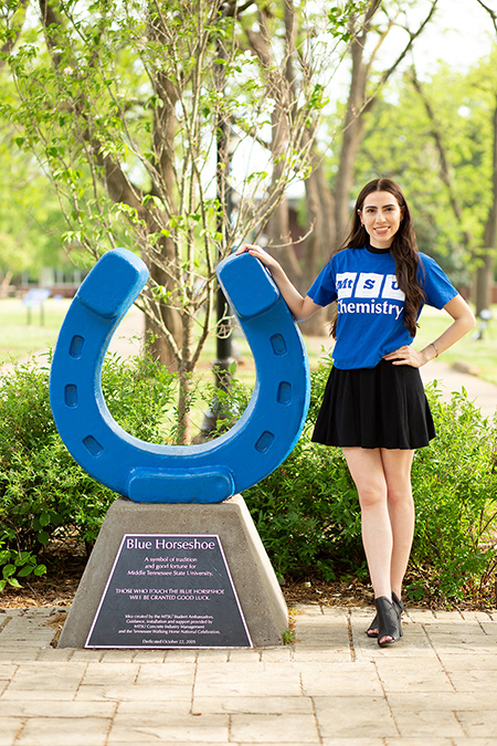 Maria Clark, Middle Tennessee State University biochemistry major and undergraduate researcher, poses with the university’s lucky horseshoe on campus in her MTSU chemistry T-shirt this past spring to commemorate her recent graduation. (Photo courtesy of Maria Clark)