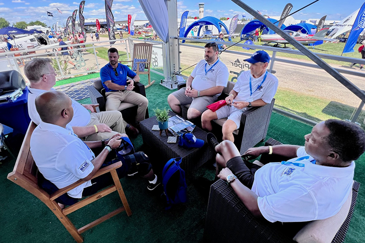 MTSU President Sidney A. McPhee, bottom right, along with university faculty and staff speak with a representative from Piper Aircraft, which provides the MTSU Aerospace Department’s twin-engine trainers, during the 2022 EAA AirVenture in Oshkosh, Wis. (MTSU photo by Andrew Oppmann)