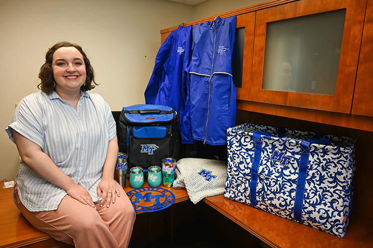 Bethany Cardenas, who works on communication projects at Middle Tennessee State University’s College of Graduate Studies, sits with a selection of MTSU-themed prizes on Aug. 16, 2022, at the Sam H. Ingram Building on campus that are available to graduate students who play the college’s new “Campus Quest!” virtual scavenger hunt that launches next week. (MTSU photo by Stephanie Barrette)