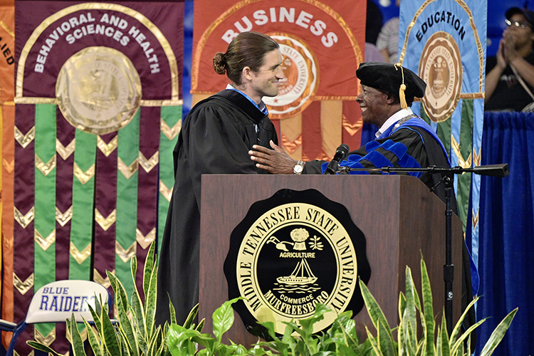 Andrew Forsthoefel, left, is welcomed to the platform by MTSU President Sidney A. McPhee Aug. 21 at the 2022 University Convocation at Murphy Center. Forsthoefel, author of "Walking to Listen," delivered the main address.