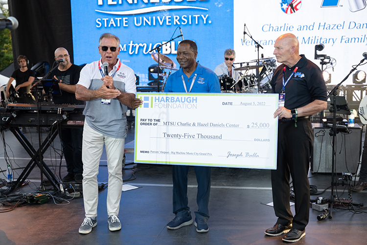 From left, Harbaugh Foundation Director Joe Balla presents a $25,000 check to MTSU President Sidney A. McPhee and retired Army Lt. Gen. Keith Huber, MTSU senior adviser for veterans and leadership initiatives, Friday, Aug. 5, at the Big Machine Music City Grand Prix in downtown Nashville, Tenn. (MTSU photo by James Cessna)