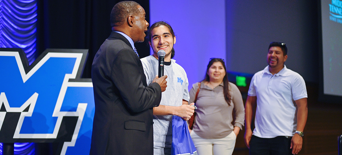 Middle Tennessee State University President Sidney A. McPhee awards prospective student Jonathan Eskobar a $15,000 scholarship while his parents, Maria and Saulramos Eskobar, look on during the kickoff event for the university’s True Blue Tour at the Student Union Building on Wednesday, Aug. 17, 2022. (MTSU photo by Cat Curtis Murphy)