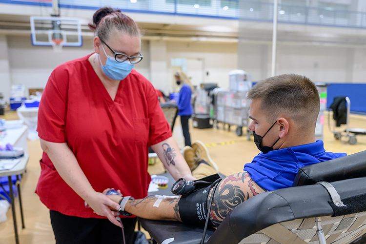 American Red Cross phlebotomist Holly Fish, left, checks Capt. Dakota Eldridge's blood pressure while he donates blood collection unit in November 2021 on the first day of MTSU's annual three-day "True Blue Blood Drive" in the Student Health, Wellness and Recreation Center. Eldridge is an assistant professor in the Department of Military Science. MTSU and Western Kentucky University are renewing their blood-drive rivalry this fall after a two-year hiatus; the winner will be announced Oct. 15. (MTSU file photo by J. Intintoli)