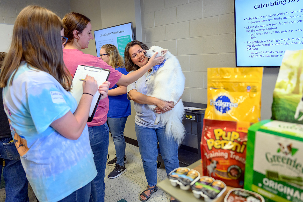 As students enjoy petting Eskie, an American Eskimo Spitz owned by Emma Penston, daughter of Casey Penston, right, with the Tennessee STEM Education Center at MTSU, they complete an assignment regarding pet nutrition in the Stark Agriculture Center Sept. 21. It was one of 20-plus activities high school students participated in during the fifth annual MTSU School of Agriculture Raider Roundup, sponsored by MT Engage and hosted by Collegiate FFA. (MTSU photo by J. Intintoli)