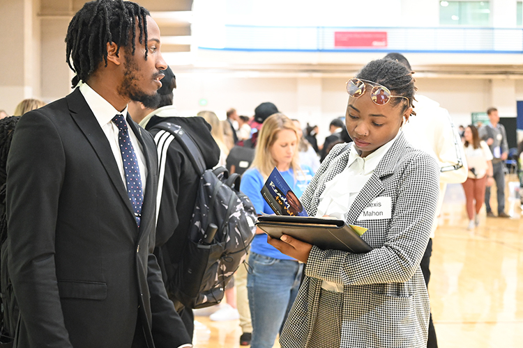 Representing car rental company Enterprise Holdings, MTSU alumnus Joshua Gray, left, chats with senior pre-law major Alexis Mahon of Memphis, Tenn., during the 2022 Fall Career Fair held Sept. 29 in the Campus Recreation Center. (MTSU photo by James Cessna)