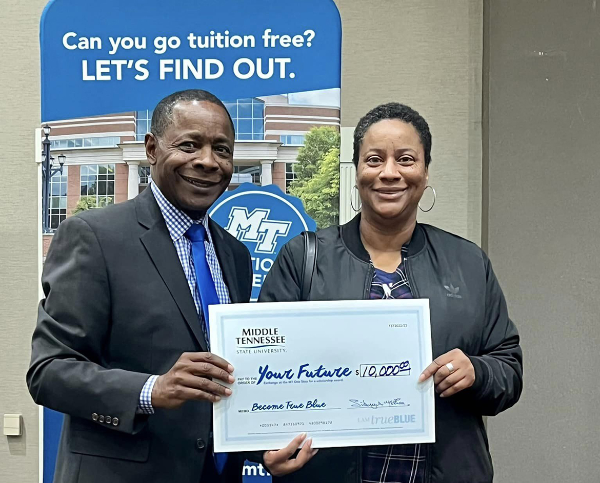 MTSU President Sidney A. McPhee, left, gives an oversized scholarship check for $10,000 to Ayanna Yarborough of Atlanta, Ga. The middle school social studies teacher was present when her nephew, Khalil Bailey of Jefferson, Ga., had his name drawn for the scholarship recently during the True Blue Tour visit to Atlanta. The event was held in The Westin Perimeter North in Sandy Springs, Ga. Bailey had attended a Georgia university when the pandemic broke out in 2020 and he dropped out of school. (MTSU photo by Andrew Oppmann)