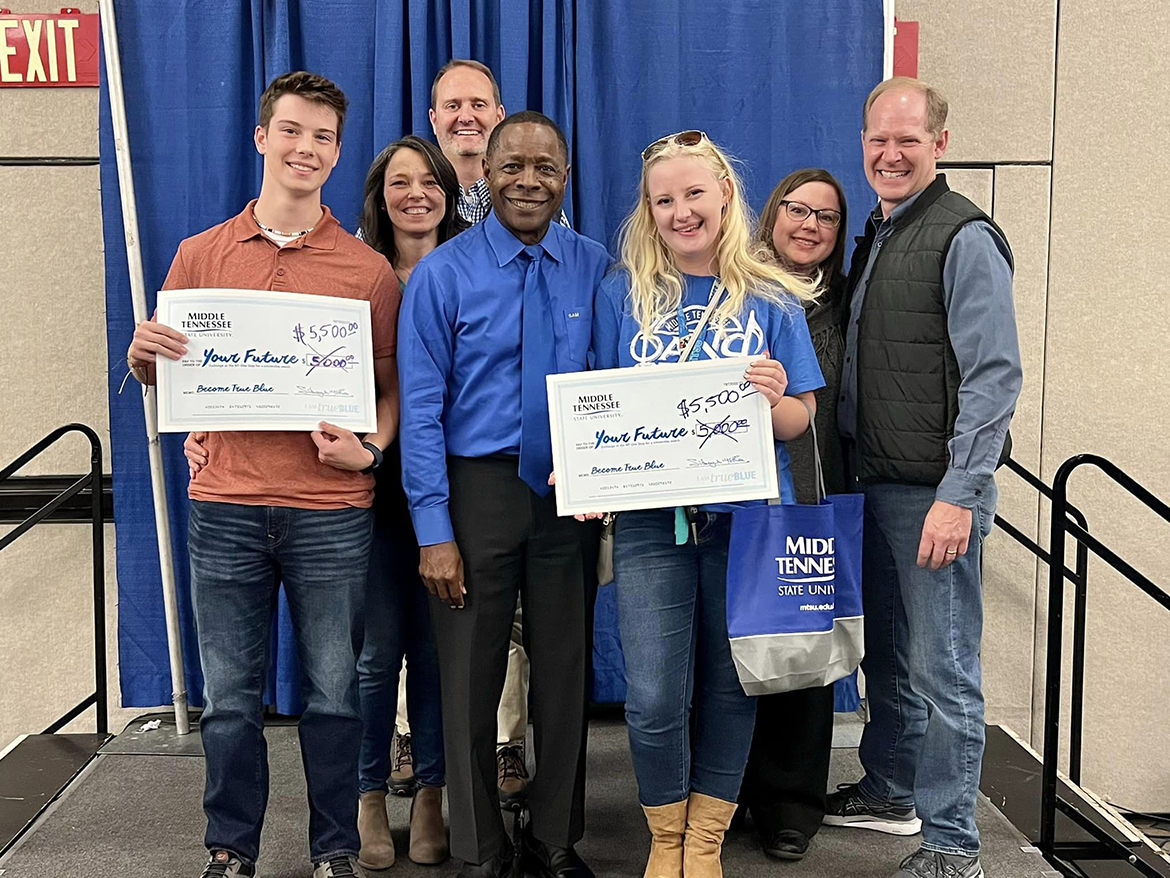 In a giving spirit in Chattanooga, Tenn., at the True Blue Tour wrap-up event, MTSU President Sidney A. McPhee, center, added an additional $500 to the $5,000 scholarships won by Luke Malone, left, of Lenoir City, Tenn., and Laci Mason of Soddy-Daisy, Tenn., at the Chattanooga Convention Center. Shown from left are Luke, Joy and Michael Malone; McPhee; and Laci, Jennifer and Robbie Mason. McPhee added the exttra money when Luke Malone told the Chattanooga crowd how much he loved the MTSU chocolate milk when he visited campus. He wants to study Aerospace proffessional pilot; Laci Mason wants to study recording industry or audio production. (MTSU photo by Andrew Oppmann)
