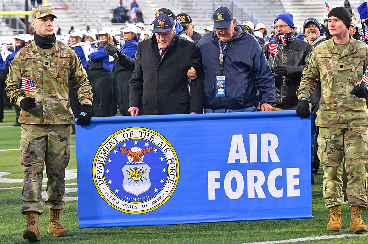 I.V. Hillis Jr., 92, second from left, of McMinnville, Tenn., leads the U.S. Air Force veterans across Horace Jones Field in Floyd Stadium Saturday, Nov. 12. The MTSU Band of Blue, in background, performed military theme songs at halftime. MTSU ROTC cadets hold the Air Force banner. Hillis is the 2022 Dr. Joe Nunley Award recipient. (MTSU photo by Cat Curtis Murphy)