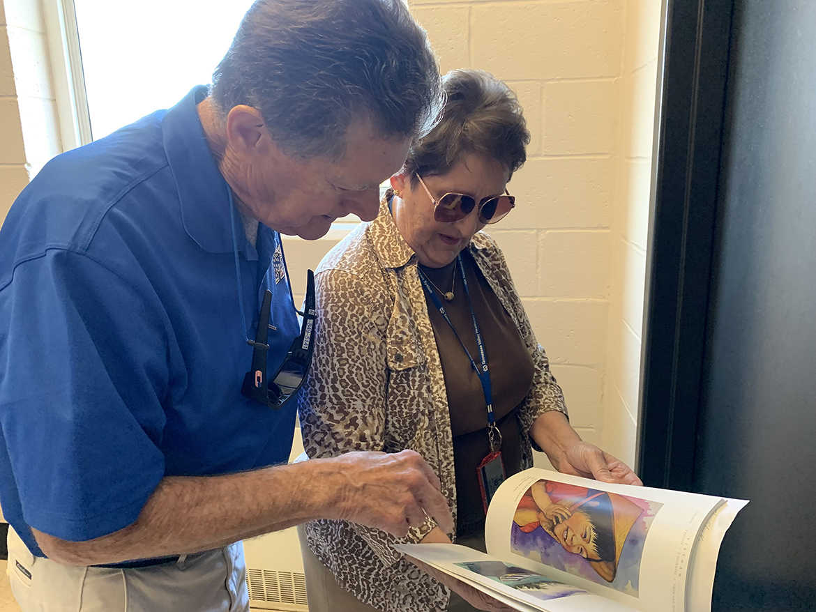 MTSU alumnus Bud Morris, left, and Betty Struzick, VA clinical social worker in the Charlie and Hazel Daniels Veterans and Military Family Center, take a quick glance at the book she purchased showing the artwork by Gallatin, Tenn., residents David Wright and Chuck Creasy. Both served in the military in Vietnam in the 1960s. (MTSU photo by Randy Weiler)