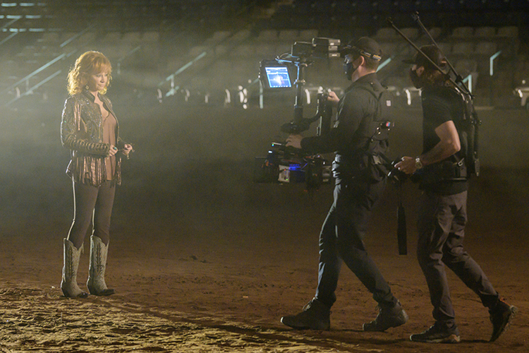 Country superstar Reba McEntire stands in a spotlight in the dusty arena of MTSU's Tennessee Miller Coliseum while MTSU alumnus Tony Reyes, center, captures her image on his Steadicam and director Shaun Silva observes during the video shoot for her duet with Cody Johnson, “Dear Rodeo,” in this October 2020 file photo. McEntire is the subject of a Dec. 8 ABC News special in which MTSU College of Media and Entertainment Dean Beverly Keel, a veteran music journalist and record company executive, will provide commentary on McEntire's life and career. (MTSU file photo by Andy Heidt)