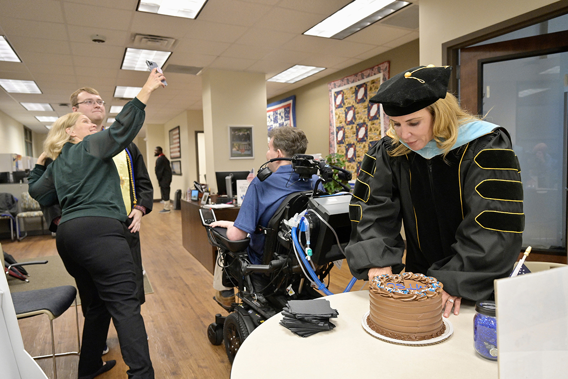 As Middle Tennessee State University Charlie and Hazel Daniels Veterans and Military Family Center Director Hilary Miller, right, slices cake for the special occasion, Wendy Trotter, left, takes a selfie with her son, Brad Trotter, as his father, Chaz, takes in the moment in the Daniels Center in the Keathley University Center Wednesday, Dec. 7. U.S. Navy veteran Chaz Trotter was diagnosed with ALS, or Lou Gehrig’s disease in 2019. Miller organized a special event attended by MTSU President Sidney A. McPhee and Deb Sells, vice president of Student Affairs, to celebrate Brad Trotter’s pending graduation since his father would not be able to attend the Saturday, Dec. 10, ceremony. (MTSU photo by Andy Heidt)