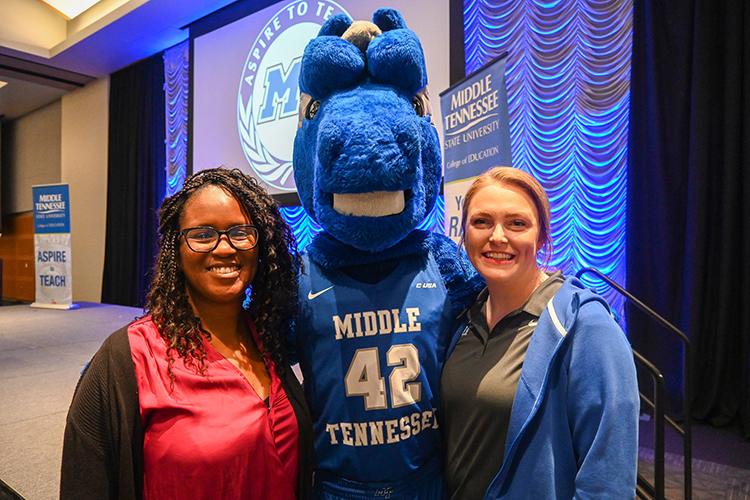 Tiffany Dellard, left, an executive director at Middle Tennessee State University’s College of Education, and Rachel Fullerton, right, assistant director of marketing for MTSU Athletics, pose with university mascot Lightning at the College of Education’s end-of-semester seminar for education graduates at the Student Union Building on Thursday, Dec. 8, 2022. Fullerton and MTSU Athletics brought $3,500 in gift cards for a giveaway drawing that were provided by the College Football Playoff Foundation. (MTSU photo by Stephanie Wagner)