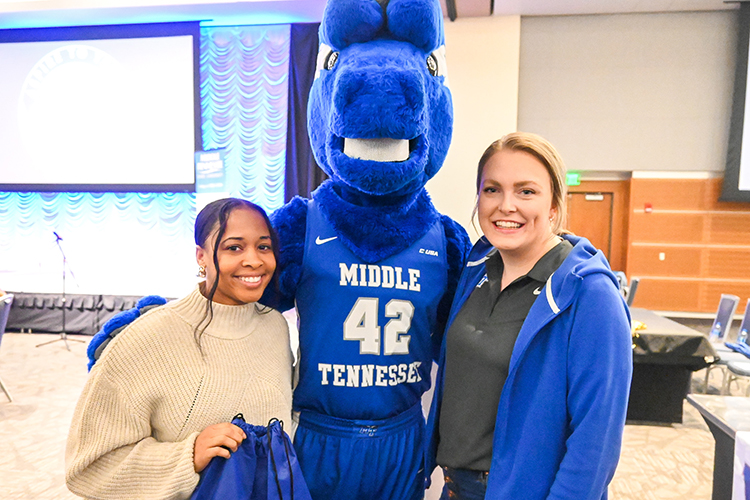 Lauren Washington, left, Middle Tennessee State University education graduate, and Rachel Fullerton, right, assistant director of marketing for MTSU Athletics, pose with university mascot Lightning at the College of Education’s end-of-semester seminar for education graduates at the Student Union Building on Thursday, Dec. 8, 2022. Washington holds an MTSU Athletics bag with a $100 Michaels gift card she won in a prize drawing at the event, courtesy of MTSU Athletics and provided by the College Football Playoff Foundation. (MTSU photo by Stephanie Wagner)