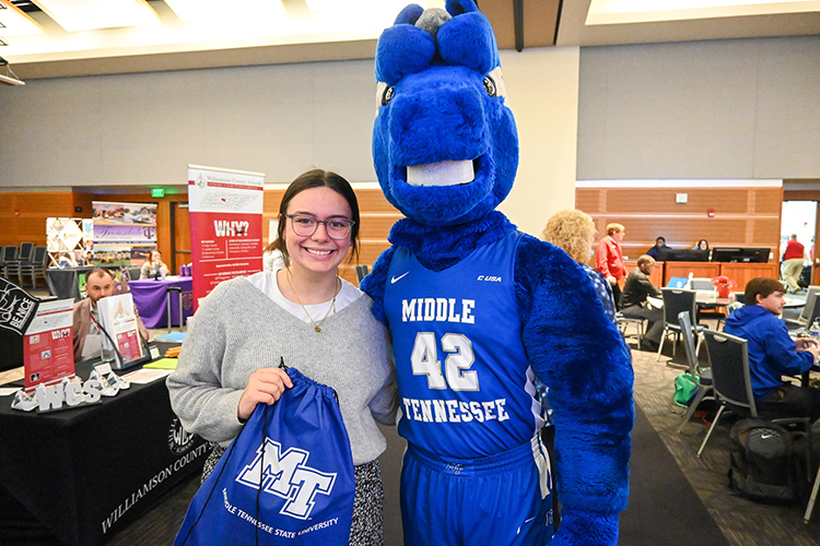 Allie Tenpenny, left, Middle Tennessee State University education graduate, poses with university mascot Lightning at the College of Education’s end-of-semester seminar for education graduates at the Student Union on Thursday, Dec. 8, 2022. Tenpenny holds an MTSU Athletics bag with a $100 Michaels gift card she won in a prize drawing at the event, courtesy of MTSU Athletics and provided by the College Football Playoff Foundation. (MTSU photo by Stephanie Wagner)