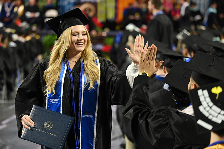 A member of MTSU's fall Class of 2022 gets a high-five from a fellow new graduate as she returns to her seat, degree in hand, in Hale/Earle Arena inside Murphy Center during the university's Dec. 10 commencement ceremonies. MTSU presented 1,698 students with their degrees — 1,345 undergraduates and 353 graduate students — to mark the first graduation of its 112th academic year. (MTSU photo by James Cessna)