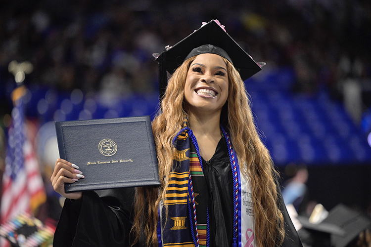A member of MTSU's fall Class of 2022 grins as she displays her new diploma to supporters in the stands in Hale/Earle Arena inside Murphy Center on during the university's Dec. 10 commencement ceremonies. MTSU presented 1,698 students with their degrees — 1,345 undergraduates and 353 graduate students — to mark the first graduation of MTSU's 112th academic year. (MTSU photo by Andy Heidt)