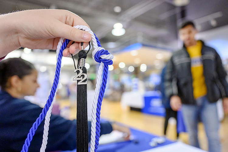 An employee of MTSU's Phillips Bookstore displays a graduation tassel with a 2022 charm and one of the blue-and-white cords distributed to University Honors College graduates during the university's Senior Celebration in the Student Union store Dec. 5. Students graduating Saturday, Dec. 10, in MTSU's fall 2022 commencement ceremonies were able to pick up regalia and learn about the university's Senior Gift Program for scholarships and other development needs, alumni services and career development. (MTSU photo by J. Intintoli)