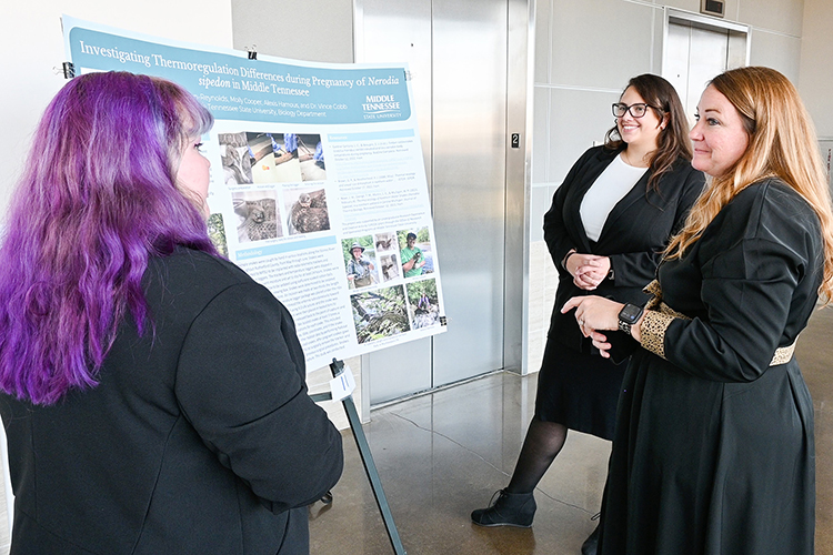Jamie Burriss, head of Middle Tennessee State University’s Undergraduate Research Center, right, listens to two undergraduate MTSU students present their research about snakes at the center’s open house event on Nov. 3, 2022, at the Science Building on campus. (MTSU photo by Stephanie Wagner)