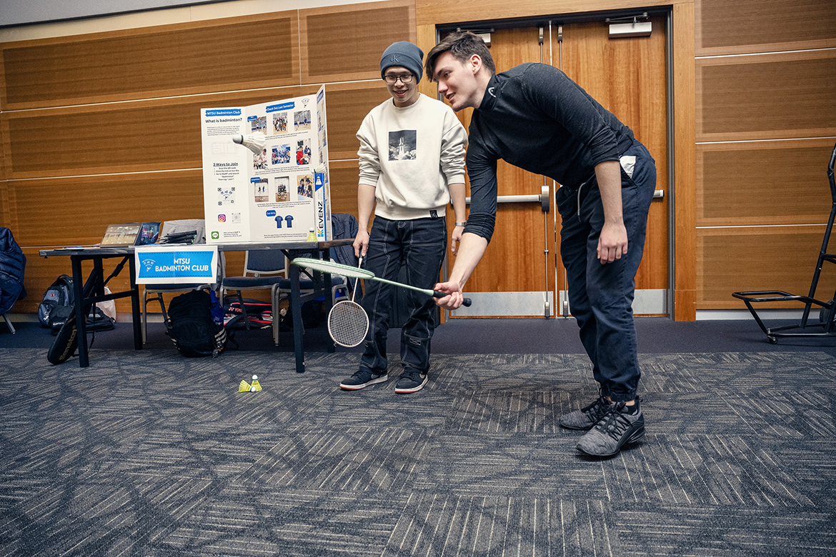 Tristan Howard, right, an MTSU junior, lifts a shuttlecock off the floor while senior Leo Sun watches during the recent Middle Tennessee State University Student Organization Fair, which included the MTSU Badminton Club as one of nearly 100 participating organizations in the Student Union Ballroom. (MTSU photo by Andy Heidt)