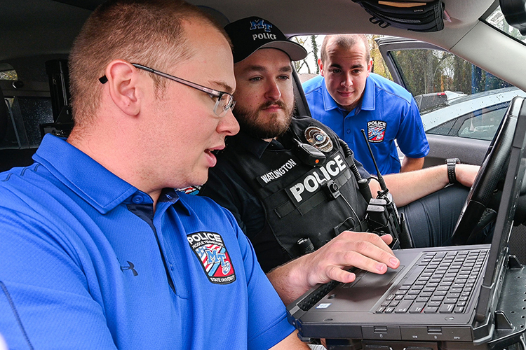 Sgt. Alex Watlington of Middle Tennessee State University’s Police Department, center, shows MTSU’s newest recruits Lealand Wood, left, and Tristan Slater how to operate a patrol vehicle’s computer on campus in November 2022. (MTSU photo by Stephanie Wagner)