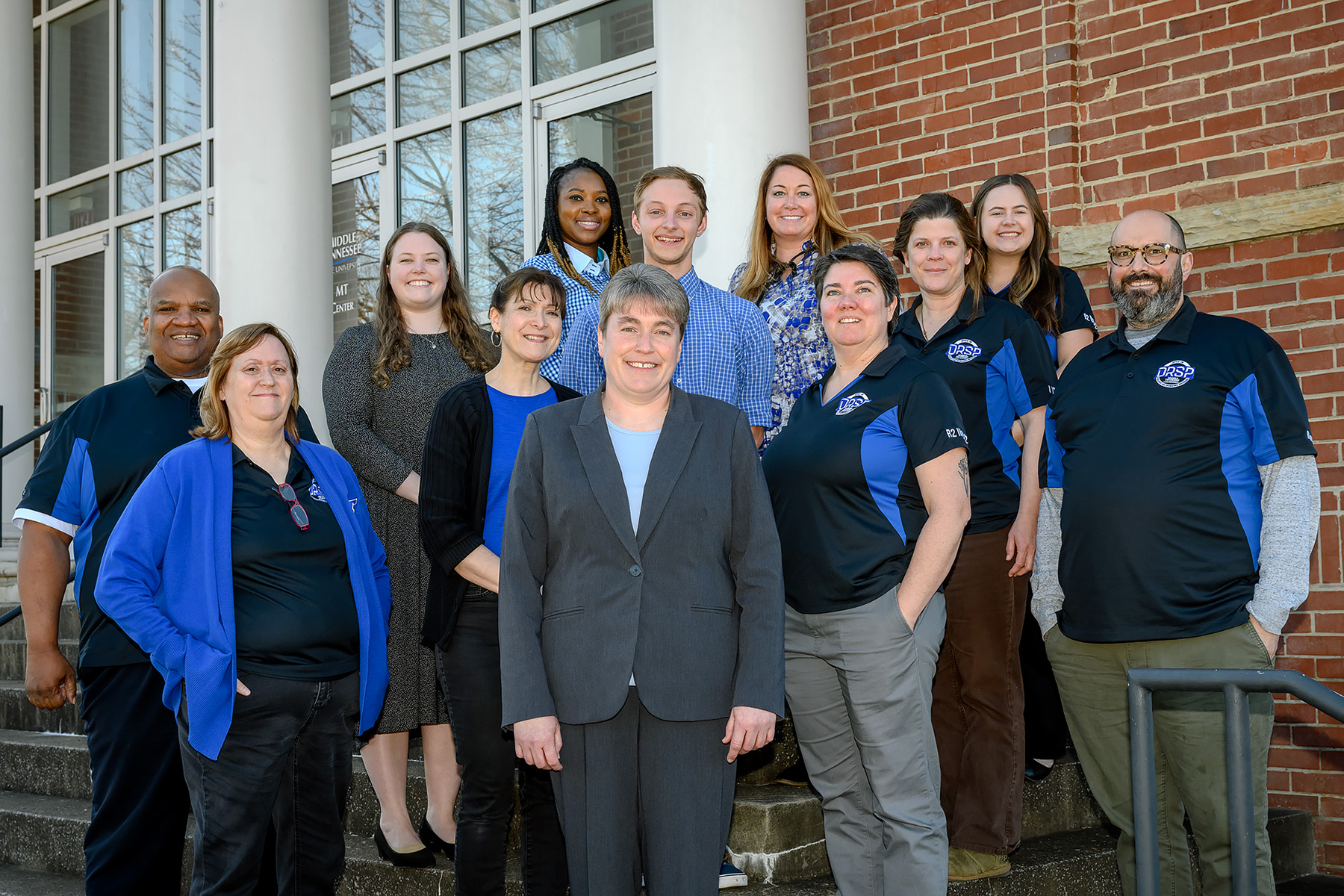 Rachel McGinnis, front row and center, new director of the Office of Research and Sponsored Programs at Middle Tennessee State University, joins her office staff for a photo in front of the Sam Ingram Building on campus on Feb. 13, 2023. McGinnis says she wants the campus community to think of the office as the “go-to resource” for research on campus. Standing in the second row, from left, are Lisa Lee, Julie Darbonne, Michelle Willard and John Sousa; third row, from left, are Keith Palmer, Katie Medrano, Jacob Grones and Janie Becker; and back row, from left, are Aanu Adekoya, Jamie Burris and Kelsey Benton. (MTSU photo by J. Intintoli)