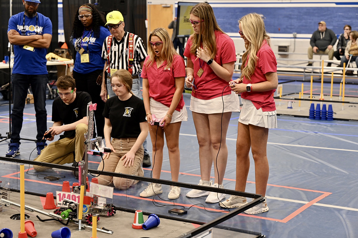 Nathan Blunkall, kneeling left, of Central Magnet School in Murfreesboro, maneuvers his robot in the ring in an early-round match at the TNFIRST First Tech Challenge Tennessee State Championship in robotics on Saturday, Feb. 18, at Middle Tennessee State University’s Alumni Memorial Gym. Other participants observing include teammate Addy Henninger and opposing team members Sydney MacMurray, Megan Quinn and Emily King. (MTSU photo by James Cessna)