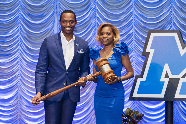 MTSU senior aerospace major Jada Powell, right, current president of the Student Government Association at Middle Tennessee State University, accepts a large gavel from Winton Cooper, former SGA president and then MTSU student, to symbolize the transfer of presidential power from Cooper to Powell at the association’s annual banquet in April 2022 on campus. (MTSU file photo by Cat Curtis Murphy)