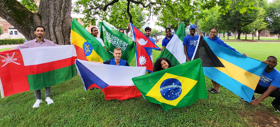 Pavel Motl, graduate student at Middle Tennessee State University and member of the International Student Council on campus, front row and center left, joins other members in holding up their countries’ flags at a council event in fall 2022 outside of the Jones Hall Building on campus. (Photo courtesy of Pavel Motl)
