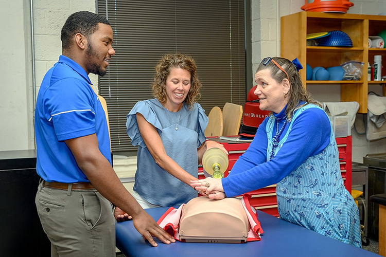 Helen Binkley, right, director of the Athletic Training master’s program at Middle Tennessee State University, and Kristi Phillips, the program’s coordinator, demonstrate a CPR technique to then student Nick Smith, now an MTSU graduate, in the summer of 2021 on campus. (MTSU file photo by J. Intintoli)