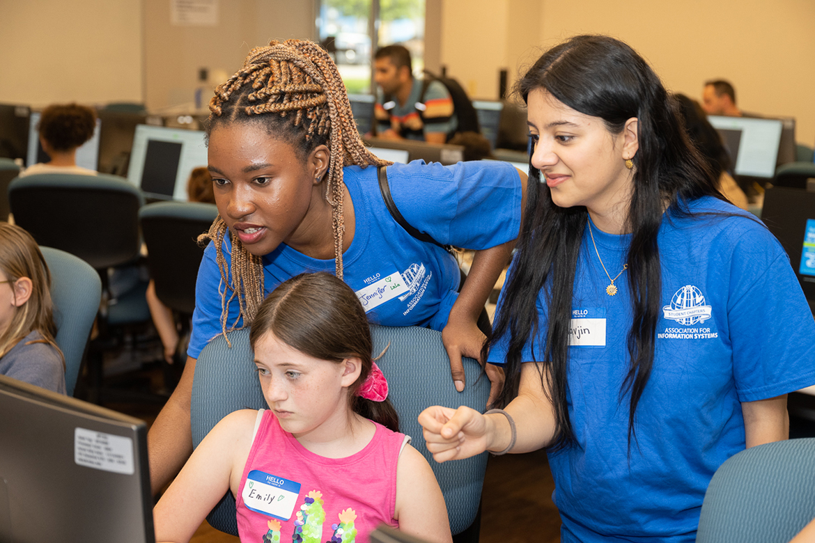 Middle Tennessee State University information systems and analytics majors Jennifer Nanmejo, a native of the central African nation of Gabon, left, and Havjin Barkhan of Nolensville, Tennessee, right, give instructions to a roomful of young girls attending the "Code Like a Girl" camp on April 15 at the Business and Aerospace Building. (MTSU photo by James Cessna)