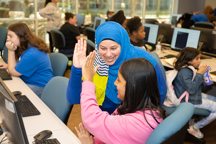 Middle Tennessee State University information systems and analytics assistant professor Sam Zaza high-fives a young participant attending the "Code Like a Girl" camp on April 15 at the Business and Aerospace Building. The free camp drew almost 30 participants. (MTSU photo by James Cessna)